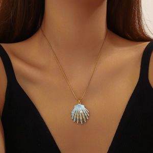 Elegant gold chain necklace featuring a blue shell pendant with a white pearl on a model