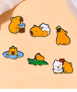 Flat lay of six unique enamel capybara pins with orange and crocodile theme details