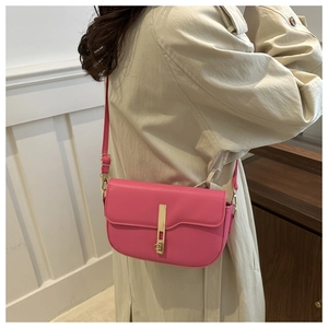 Detailed view of pink PU leather saddle bag featuring a gold metal buckle on a model