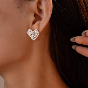 Close-up of silver heart lace stud earring with hollow mesh design worn by a model