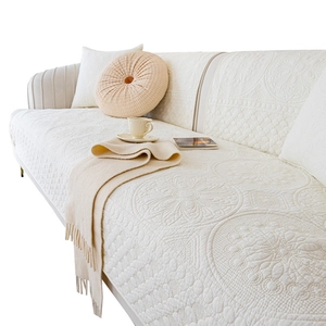 Minimalist cream quilted cotton sofa cover set with circular patterns on a white couch