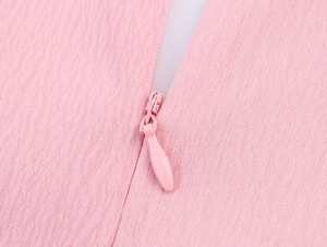 Detail of pink dress featuring textured fabric and matching invisible zipper close-up view