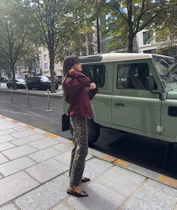 Detail of burgundy bomber jacket and leopard print pants for women's stylish autumn wear