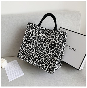 Detailed view of leopard print tote bag texture on a gray sofa with minimalist props