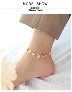 Elegant gold daisy flower anklet worn by a model against a minimalist fabric background