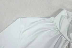 Close-up of white bodycon jumpsuit shoulder stitching and neckline texture details