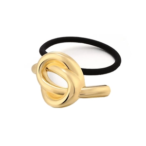 Macro detail of gold-tone knot alloy decor and elastic black rubber hair tie