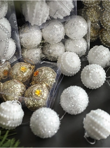 Close-up of white pearl, glitter, and gold sequin Christmas balls in a gift box