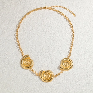 Gold stainless steel necklace with three snail spiral pendants on a white textured background