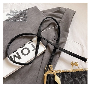 Detail view of retro black wrinkled bag with vintage floral relief and golden metal clasp