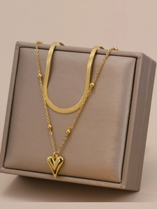 Dettaglio della collana a strati in acciaio dorato con catena a serpente e cuore pendente