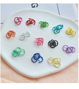Close-up of colorful lacquer jump rings for DIY jewelry making on white ceramic tray