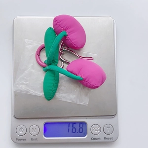 Detail showing the lightweight 16.8g handmade fabric cherry keychain on a digital scale