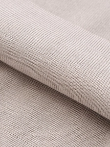 Detailed macro view of soft beige knitted fabric texture showing premium fine material quality