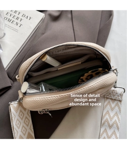 Makroansicht der geräumigen Innenfächer der cremeweißen Tasche mit Litschi-Textur