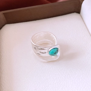 Macro detail of turquoise gemstone and hammered texture on the silver open ring