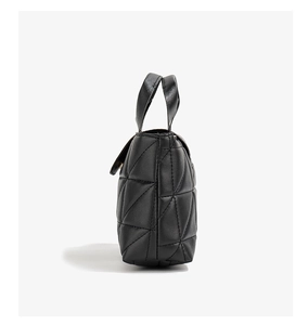 Side view of black faux leather handbag with triangle quilted stitching and dual handles