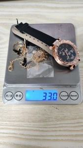 Close-up of butterfly watch set on digital scale showing a total weight of 33.0g