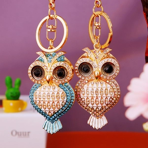 Detailed view of diamond-studded owl keychains in blue and white gold finishes