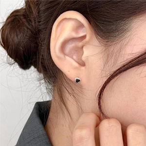 Minimalist 925 sterling silver heart-shaped stud earrings with black finish worn by a model