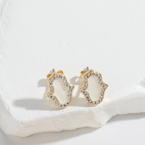 Macro shot of gold Hamsa hand stud earring with white inlay and sparkling zircons