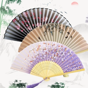 Detailed macro view of three patterned bamboo folding fans with elegant purple silk tassels