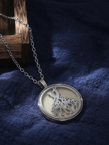 Detailed view of silver necklace with circular openwork pendant featuring giraffe motifs