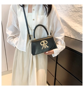 Close-up of black PU leather bag with golden letter R hardware and adjustable strap