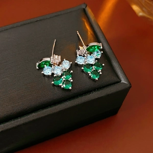 Macro shot of silver stud earrings with cluster of green and blue cubic zirconia stones