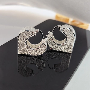 Silver vintage heart earrings with luxury floral pattern on a black mirror surface