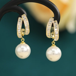 Close-up of pearl drop earrings with gold-toned zircon base on a jewelry display stand