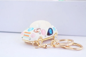 Detail of white car-shaped keychain with colorful rhinestones and gold metal chain