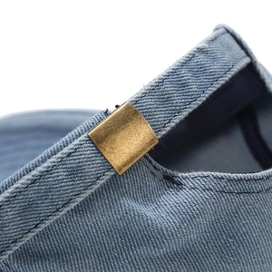 Macro view of adjustable bronze metal buckle on vintage washed blue denim baseball cap