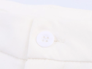 Vue macro d'un bouton blanc à quatre trous et texture raffinée du tissu du pantalon droit