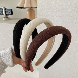 Three knitted padded headbands in black, beige, and brown featuring a woven texture design