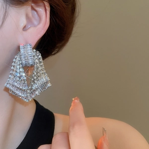 Close-up of geometric rhinestone tassel earrings worn by a model in silver finish