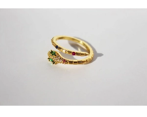 Macro shot of gold snake ring with green and red zircon stones on a white background