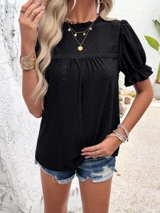Detail of black short sleeve top featuring ruffled neckline and textured fabric on model