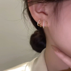 Gold plated hoop earring set with cubic zirconia stones worn on ear for minimalist look