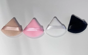Close-up of four soft triangular powder puffs in skin, pink, white, and black velvet