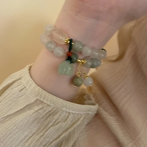 Detail of double-layer beaded bracelet with green and pink gemstones on wrist