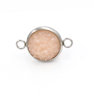 Macrodetail van een ronde roze druzy connector met verzilverde roestvrijstalen lussen