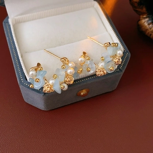 Macro view of aquamarine flower earrings with pearls in an elegant velvet jewelry box