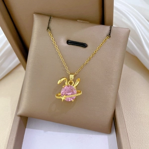 Detail of pink crystal rabbit planet necklace on premium brown jewelry pad display