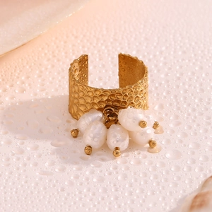 Macro detail of hammered 18K gold plated ring featuring white baroque pearl tassels