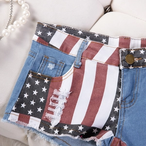 Dettaglio di pantaloncini in denim consumato con stampa bandiera USA e bordi a taglio vivo