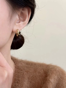 Vue détaillée d'une boucle d'oreille nœud dorée avec zircone sur un modèle