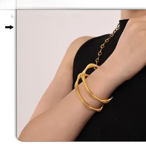 Detail of gold-plated wavy cuff bracelet with spiral texture on model's wrist