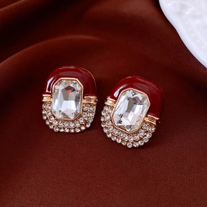 Detail of vintage palace style earrings with wine red enamel and crystals on velvet