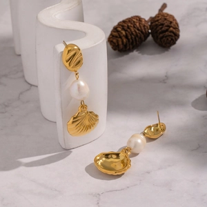 Macro detail of French vintage shell pearl drop earrings on a white marble display stand
